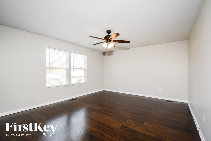 A room with a ceiling fan and wooden flooring.