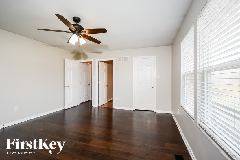 A room with a ceiling fan and wooden floors.