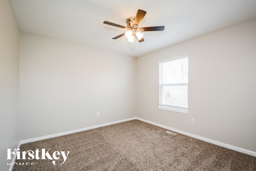 A room with a ceiling fan and a window with blinds.