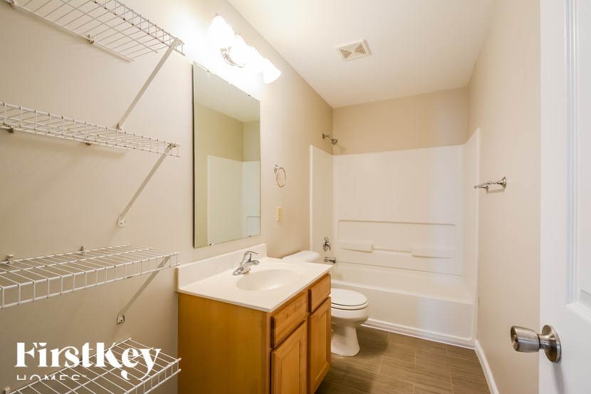 A bathroom with a toilet, sink, and mirror.