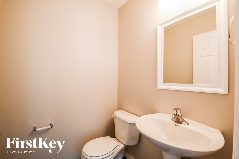 A bathroom with a toilet, sink and mirror.