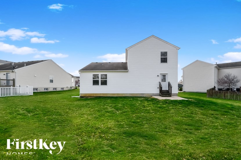 A white house with a black roof is surrounded by a grassy field.