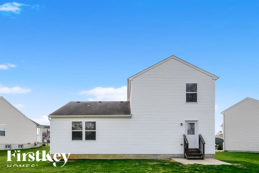 A white house with a black roof and a small porch.