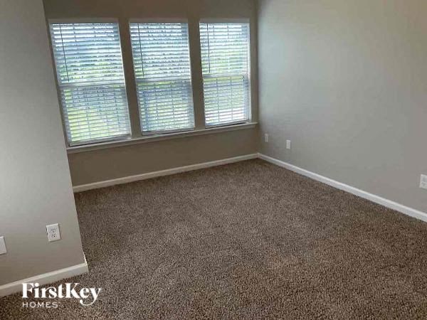 A room with a carpeted floor and a window with blinds.
