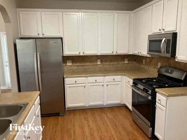 A kitchen with white cabinets and a stainless steel refrigerator.