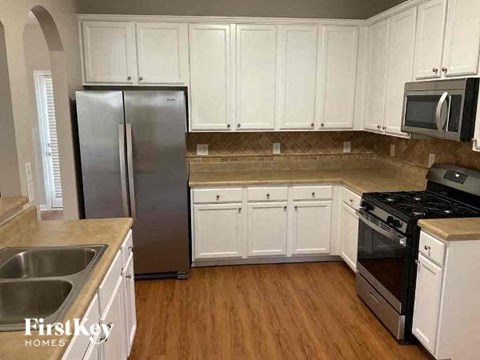 A kitchen with white cabinets and a stainless steel refrigerator.