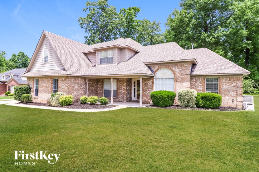 A brick house with a large front yard and a clear blue sky.