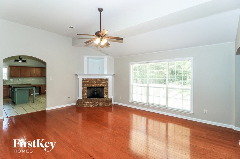 A large empty room with a fireplace and a ceiling fan.