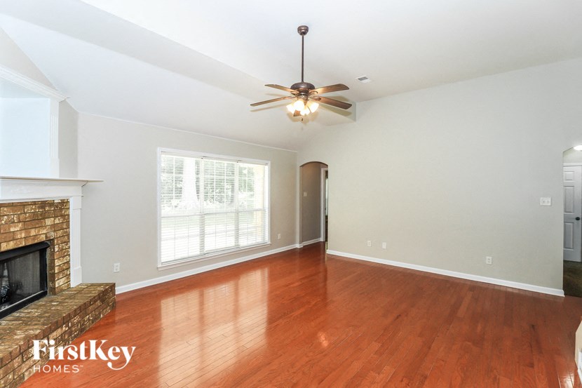 A spacious room with a fireplace and a ceiling fan.