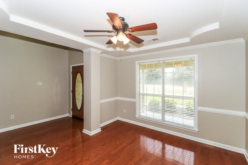 A room with a ceiling fan and a window with blinds.