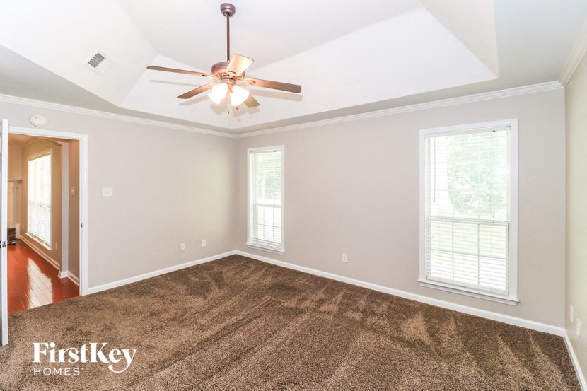 A room with a ceiling fan and carpeted floor.