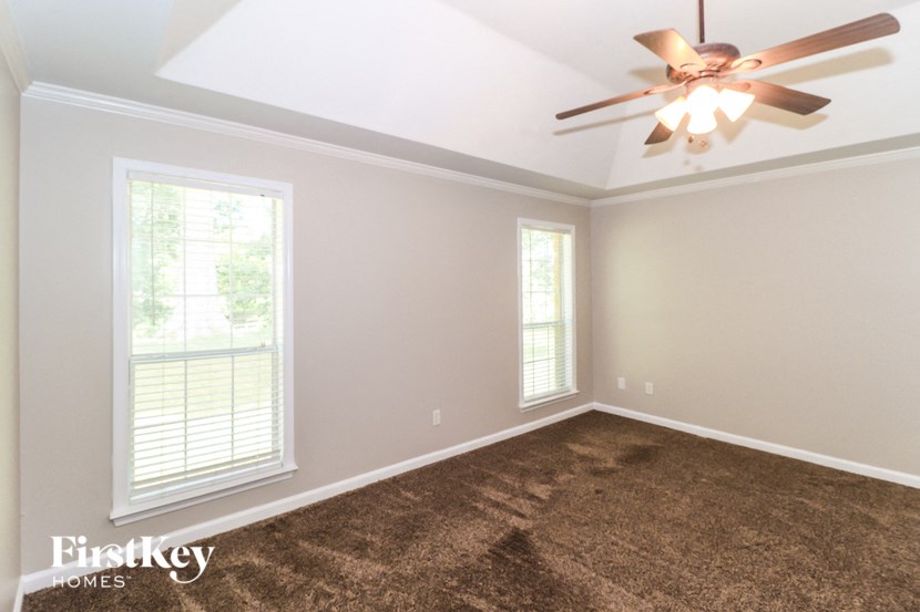 A room with a ceiling fan and two windows.