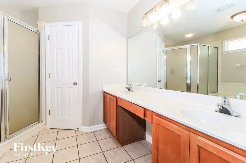 A bathroom with a sink, mirror, and shower.