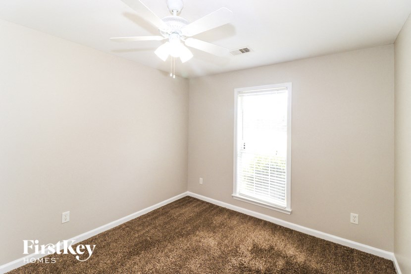 A room with a carpeted floor and a ceiling fan.