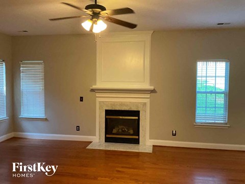 A living room with a fireplace and a ceiling fan.