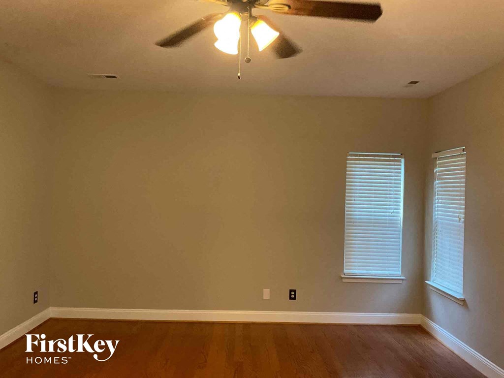 A room with a ceiling fan and wooden floors.