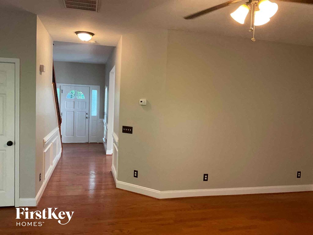 A long hallway with wood floors and a ceiling fan.