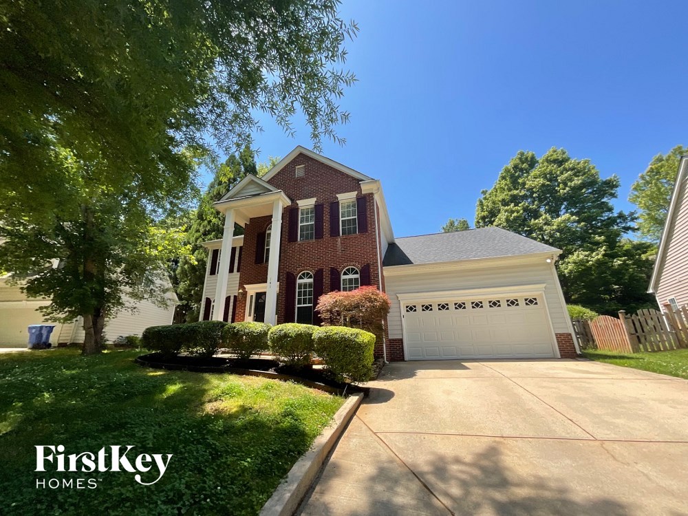 A house with a red brick exterior and a white garage door is for sale.