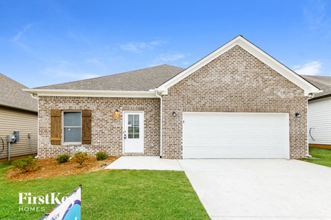 A brick house with a white garage door and a sign that says "FirstKo Homes".