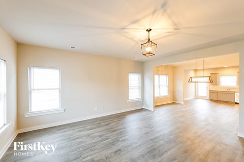 A spacious room with wooden floors and a hanging light fixture.