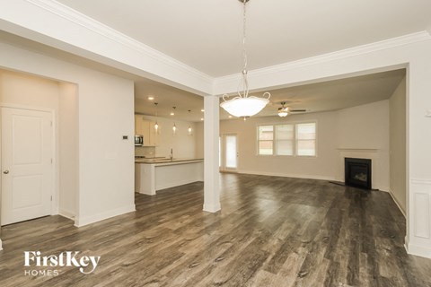 an empty living room with a fireplace and a kitchen