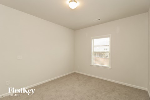 a bedroom with white walls and a window