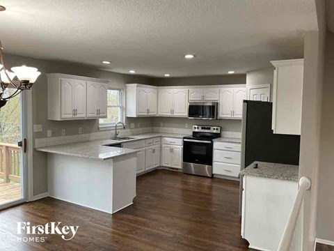 A kitchen with white cabinets and a black refrigerator.