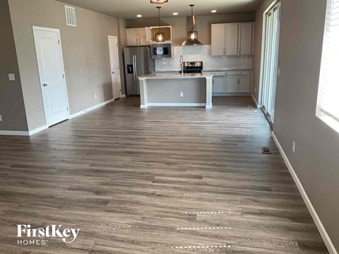 A spacious kitchen with wooden flooring and a white door.