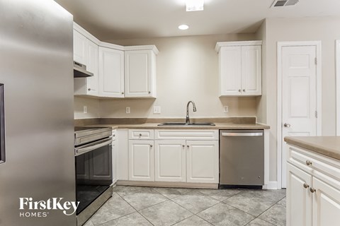 A kitchen with white cabinets and a stainless steel refrigerator.