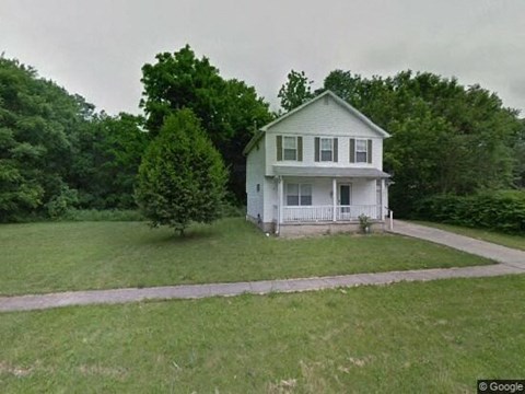 A white house with a green lawn in front.