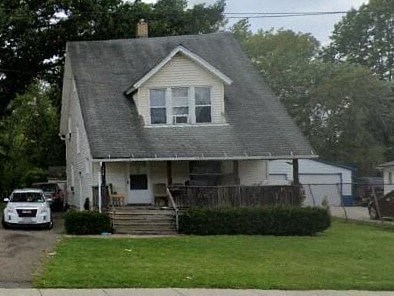 A white house with a grey roof and a car parked in front.