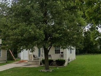 A tree in front of a white house.