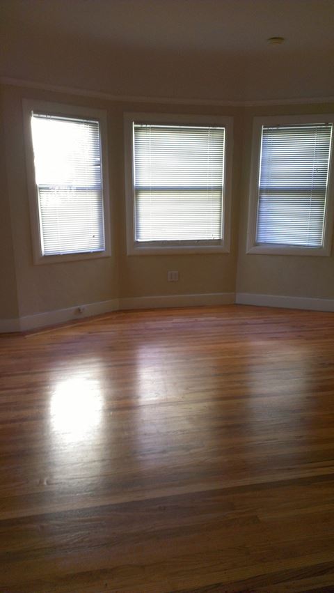 a living room with a hard wood floor and three windows