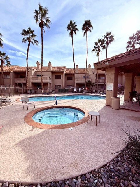 A pool surrounded by palm trees and a building.