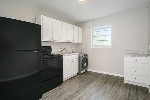 a kitchen with black appliances and white cabinets and a washing machine