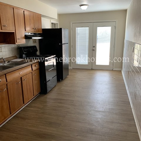 A kitchen with wooden cabinets and a black refrigerator.