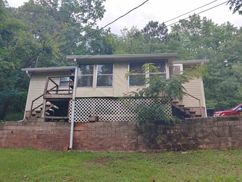 a yellow house with a brick wall in front of it