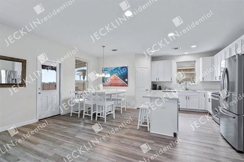 A modern kitchen with white cabinets and a wooden floor.