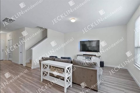 A living room with a white couch and a television on the wall.