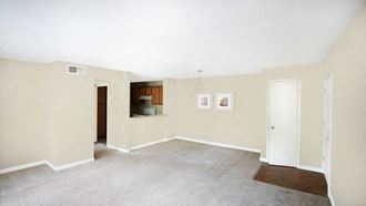 the living room and kitchen of an empty home with white walls and carpet
