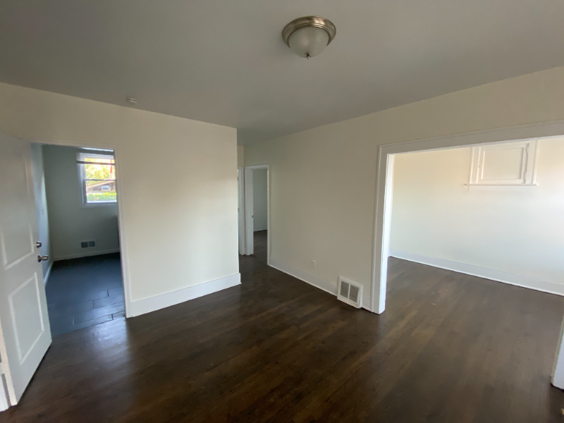 an empty living room with wood floors and white walls