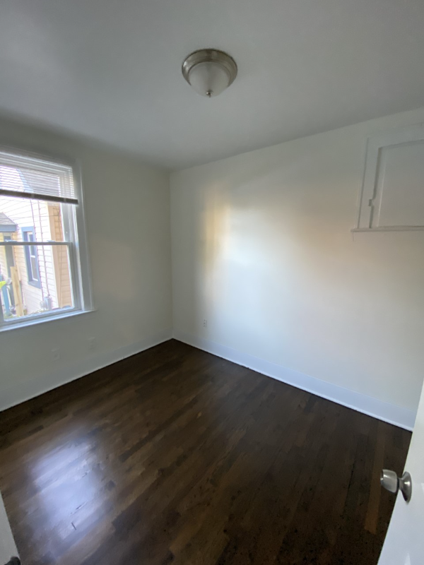an empty room with wooden floors and a window