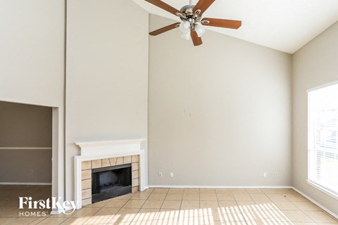 A living room with a fireplace and a ceiling fan.