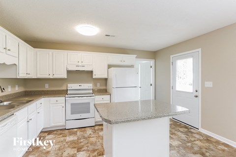 A kitchen with white cabinets and a granite countertop.