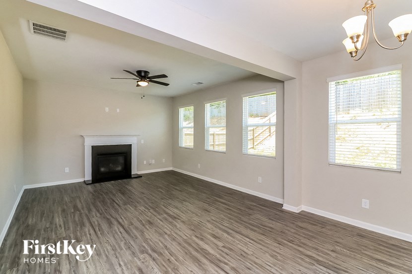 an empty living room with a fireplace and a ceiling fan