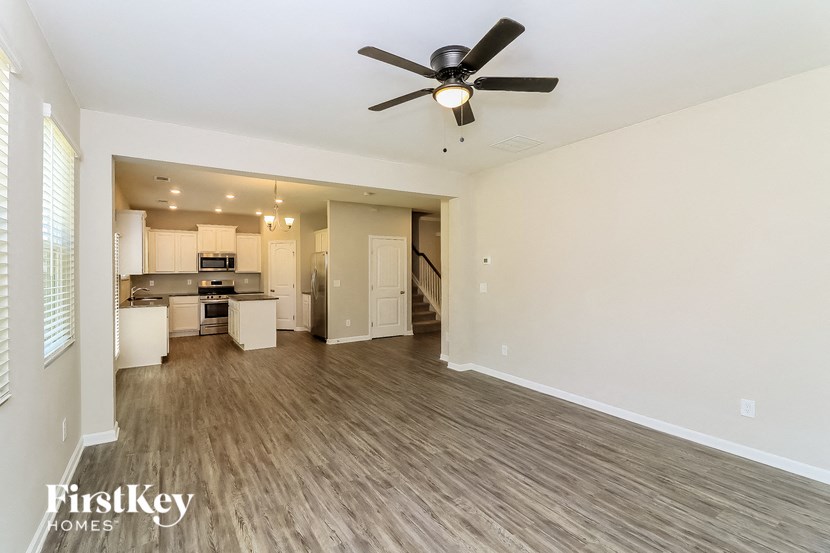 an empty living room and kitchen with a ceiling fan