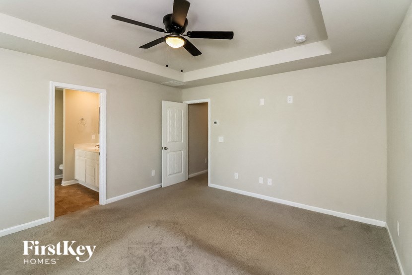 an empty living room with a ceiling fan and a bathroom