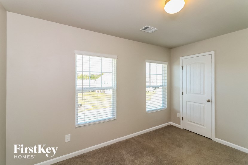 a bedroom with a white door and two windows