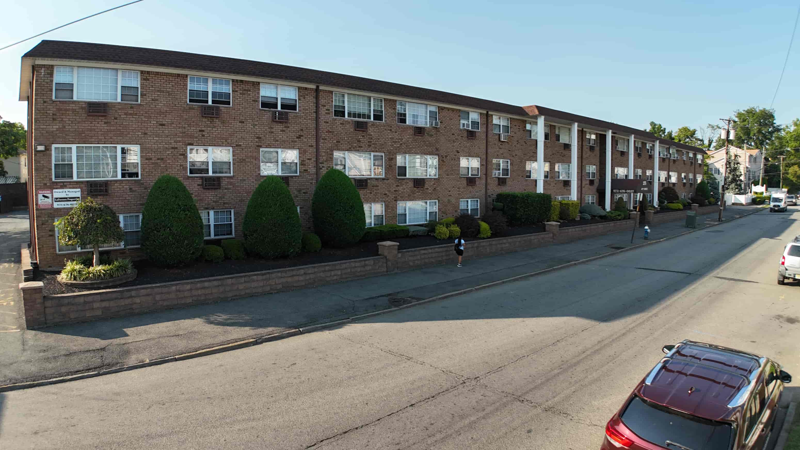 A street view of a residential area with apartment buildings and parked cars.
