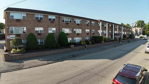 A street view of a residential area with apartment buildings and parked cars.